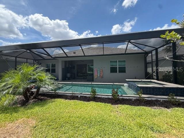 back of house featuring a yard, stucco siding, glass enclosure, and a pool with connected hot tub