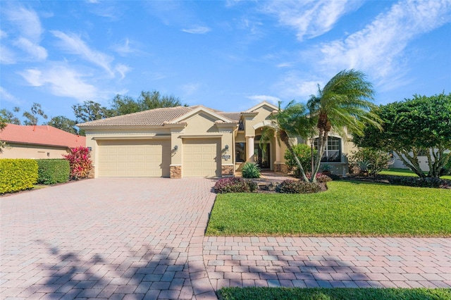 mediterranean / spanish-style house featuring a front lawn, decorative driveway, stucco siding, a tiled roof, and an attached garage