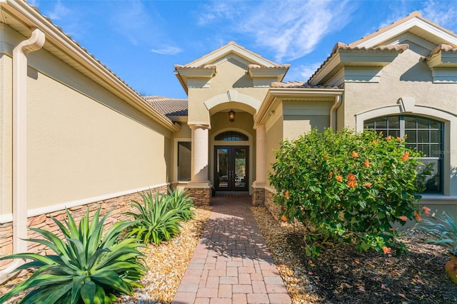property entrance featuring a tiled roof, french doors, and stucco siding