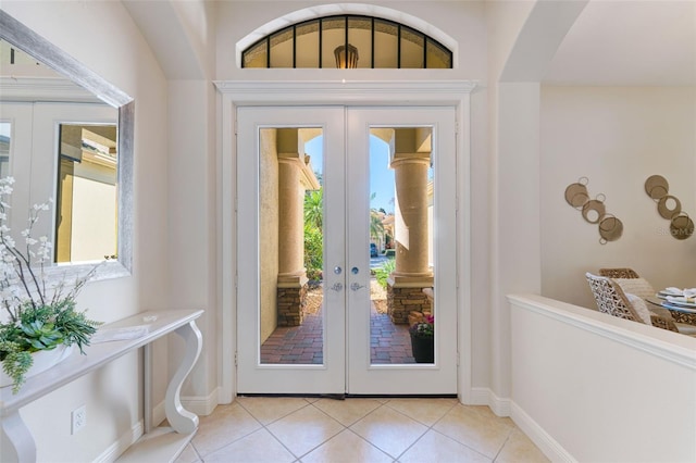 doorway to outside featuring baseboards, french doors, arched walkways, and light tile patterned flooring