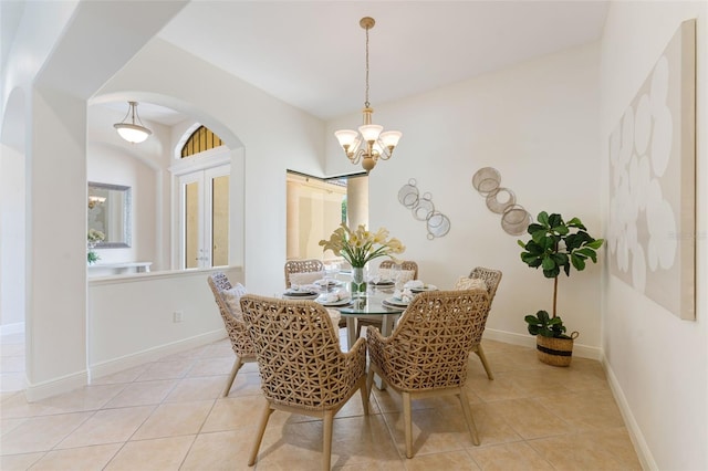 dining area featuring baseboards, arched walkways, light tile patterned floors, and a notable chandelier