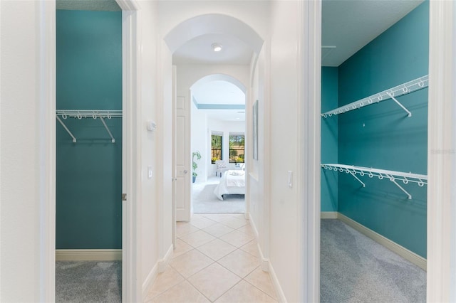 interior space featuring carpet floors, arched walkways, and baseboards