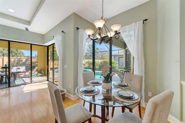 dining space featuring wood-type flooring, baseboards, and an inviting chandelier