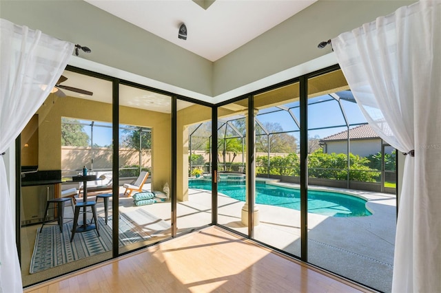 entryway featuring a sunroom, a ceiling fan, and wood finished floors