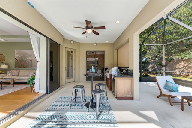 sunroom featuring a ceiling fan, exterior kitchen, and a healthy amount of sunlight