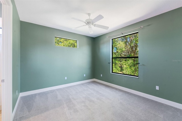unfurnished room with carpet floors, a ceiling fan, and baseboards