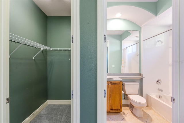 full bath featuring shower / tub combination, a walk in closet, tile patterned flooring, vanity, and toilet