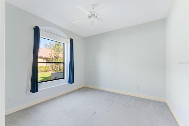 spare room with baseboards, ceiling fan, and light colored carpet