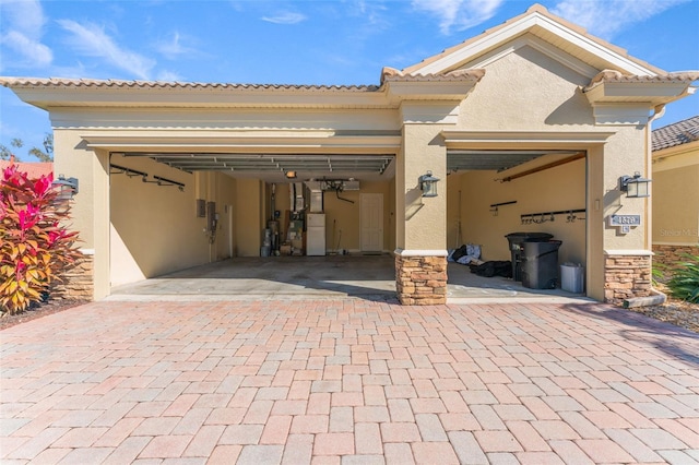 exterior space with decorative driveway, an attached garage, and stucco siding