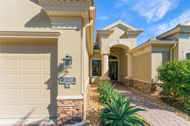 view of front of property featuring a garage, stucco siding, and stone siding