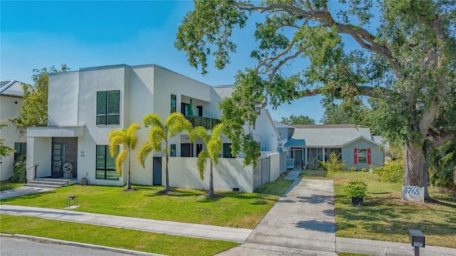 view of front of property featuring concrete driveway, stucco siding, and a front lawn