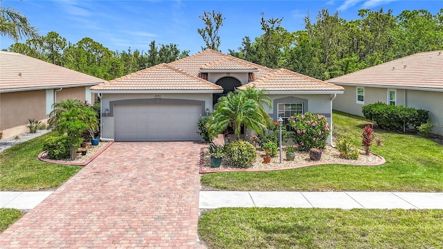 mediterranean / spanish house featuring decorative driveway, a garage, stucco siding, a tile roof, and a front yard