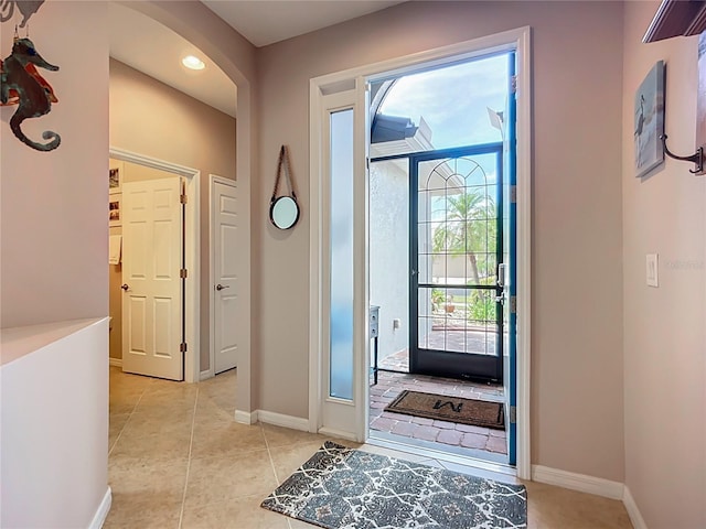 foyer entrance with arched walkways, light tile patterned flooring, baseboards, and recessed lighting