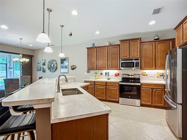 kitchen with appliances with stainless steel finishes, a sink, brown cabinetry, decorative light fixtures, and recessed lighting