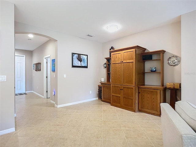 corridor with arched walkways, baseboards, and light tile patterned flooring