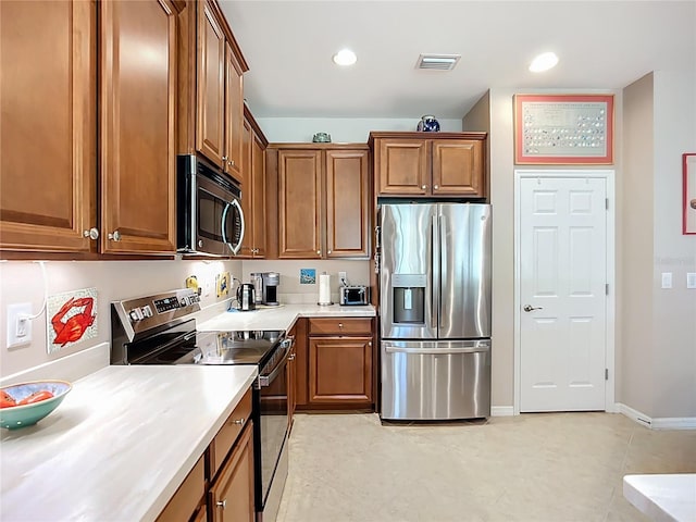 kitchen featuring baseboards, visible vents, brown cabinets, light countertops, and appliances with stainless steel finishes