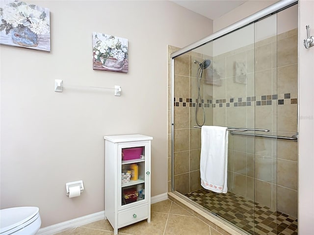 full bathroom with a shower stall, tile patterned floors, toilet, and baseboards