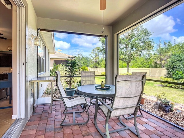 sunroom / solarium featuring outdoor dining space and ceiling fan
