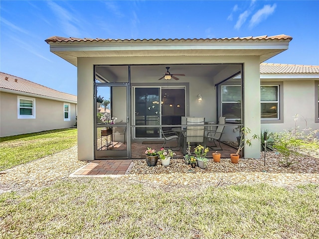 doorway to property featuring a yard, stucco siding, a tiled roof, and ceiling fan