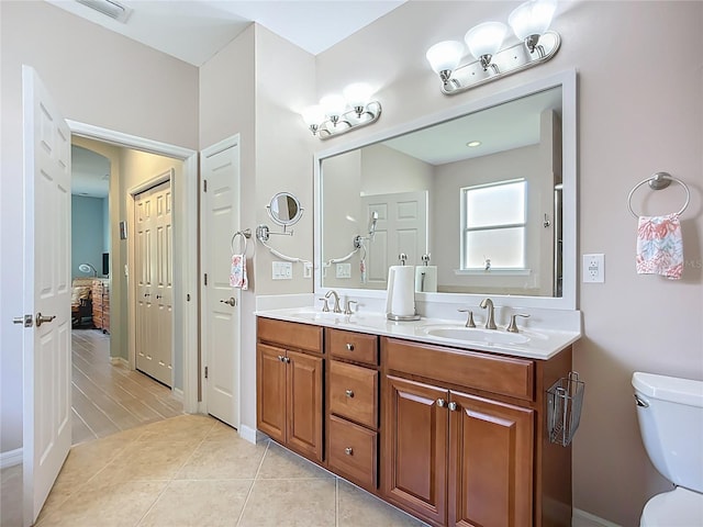bathroom with toilet, double vanity, connected bathroom, and baseboards