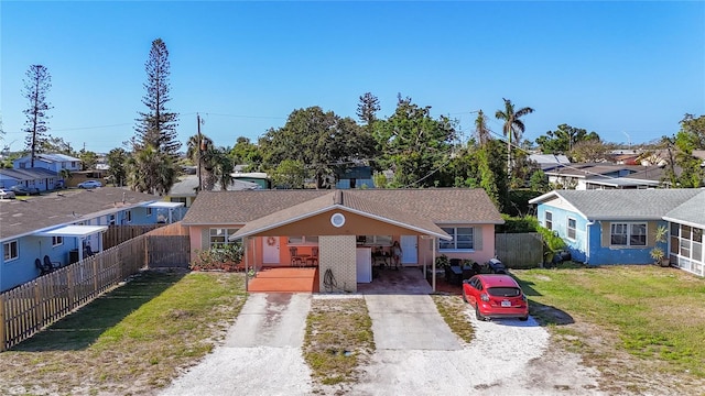 single story home featuring fence, a front yard, concrete driveway, a residential view, and a carport