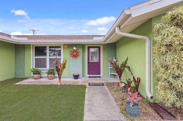 entrance to property with roof with shingles, covered porch, stucco siding, and a yard