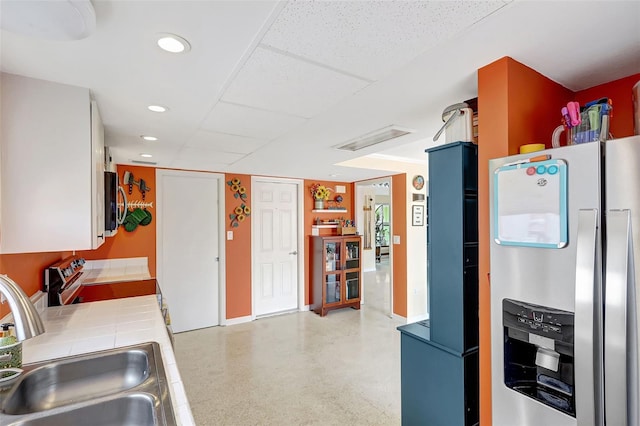 kitchen with a sink, stainless steel appliances, tile countertops, recessed lighting, and visible vents