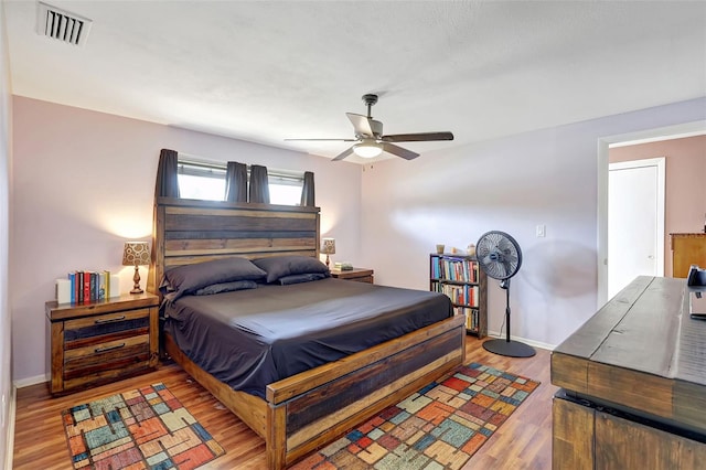 bedroom featuring a ceiling fan, baseboards, visible vents, and wood finished floors