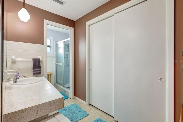full bath with visible vents, tile walls, a shower stall, vanity, and tile patterned floors