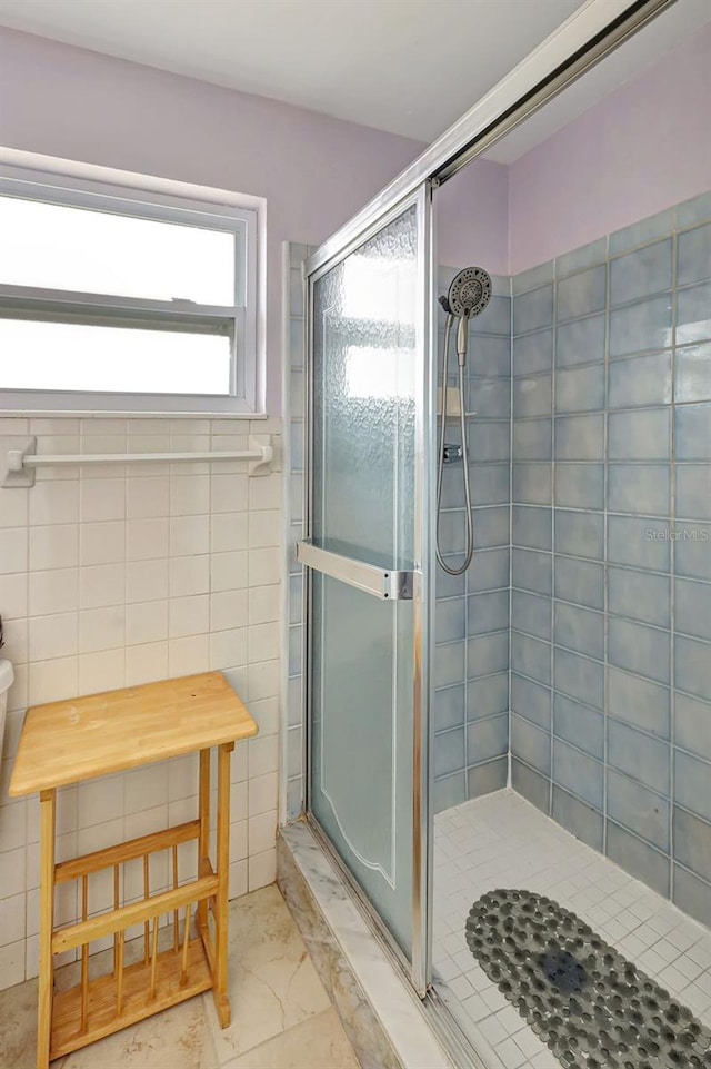 bathroom featuring marble finish floor and a shower stall
