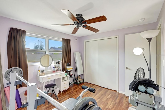 exercise room with a ceiling fan and wood finished floors