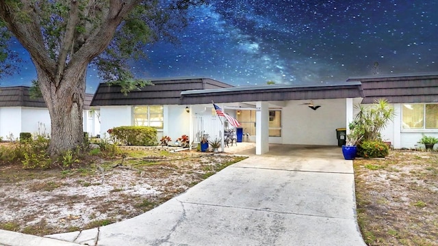 view of front of property featuring stucco siding, a carport, concrete driveway, and mansard roof