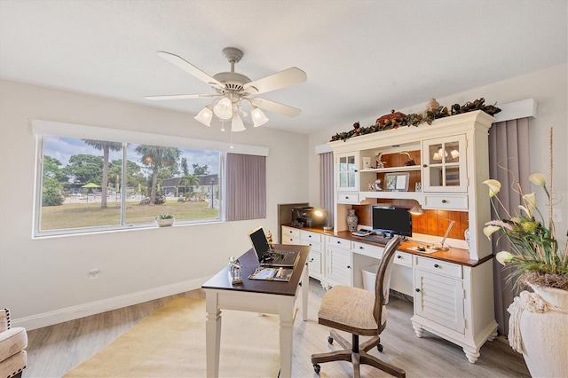 home office featuring plenty of natural light, light wood finished floors, baseboards, and ceiling fan