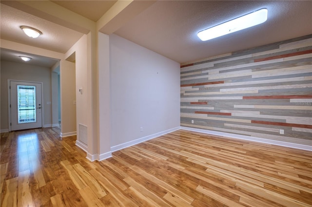 11924 Persian Ter, Bradenton, FL 34212 - empty room featuring light wood-style flooring, wood walls, a textured ceiling, baseboards, and an accent wall