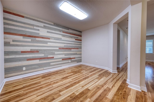 11924 Persian Ter, Bradenton, FL 34212 - spare room featuring an accent wall, wood finished floors, a textured ceiling, wooden walls, and baseboards