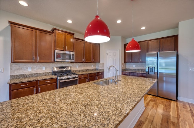 11924 Persian Ter, Bradenton, FL 34212 - kitchen featuring stainless steel appliances, a sink, light wood-type flooring, pendant lighting, and stone countertops