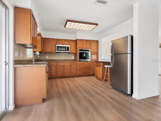 6116 Rodgers Ave, Sarasota, FL 34231 - kitchen with visible vents, light wood-style floors, brown cabinets, and stainless steel appliances