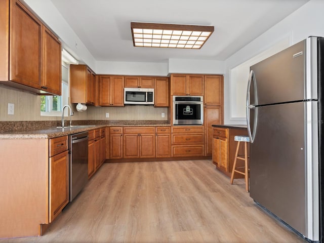 6116 Rodgers Ave, Sarasota, FL 34231 - kitchen with a sink, appliances with stainless steel finishes, light wood-style floors, and brown cabinets