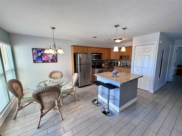 kitchen with an inviting chandelier, wood tiled floor, and appliances with stainless steel finishes