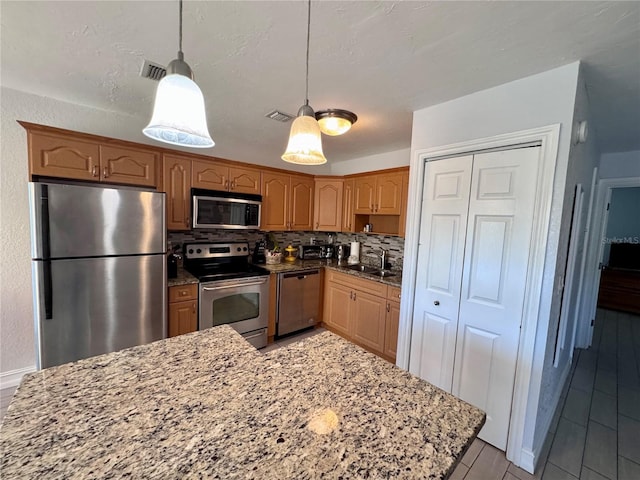 kitchen with stainless steel appliances, light stone counters, and visible vents