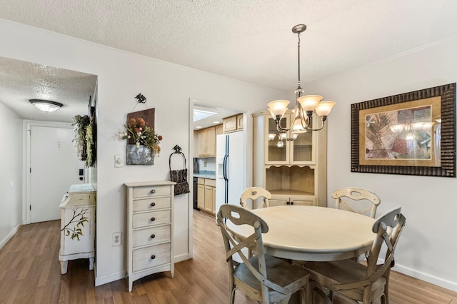 4015 Lake Bayshore Dr Unit 108, Bradenton, FL 34205 - dining room with light wood-style flooring, a notable chandelier, a textured ceiling, baseboards, and ornamental molding