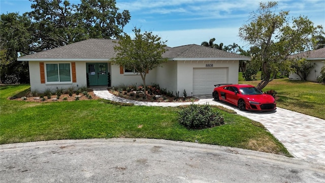 single story home featuring an attached garage, decorative driveway, a front lawn, and stucco siding