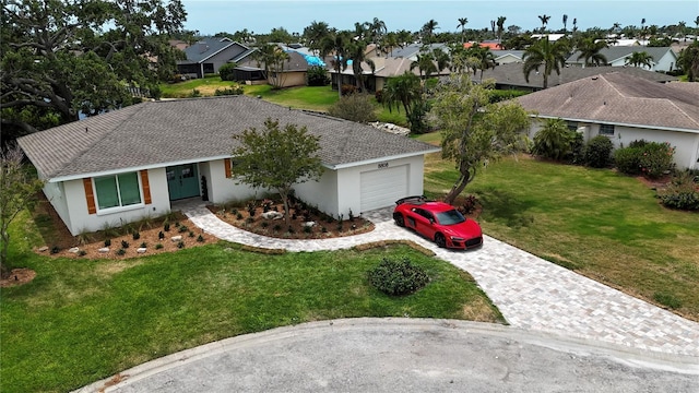 single story home featuring a garage, a front yard, decorative driveway, stucco siding, and a residential view