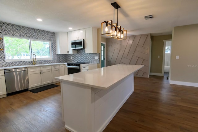 kitchen featuring white cabinets, stainless steel appliances, dark wood-type flooring, backsplash, and visible vents