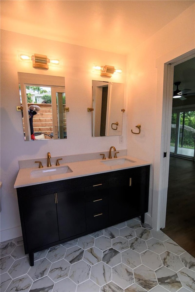 full bath with double vanity, a sink, and baseboards