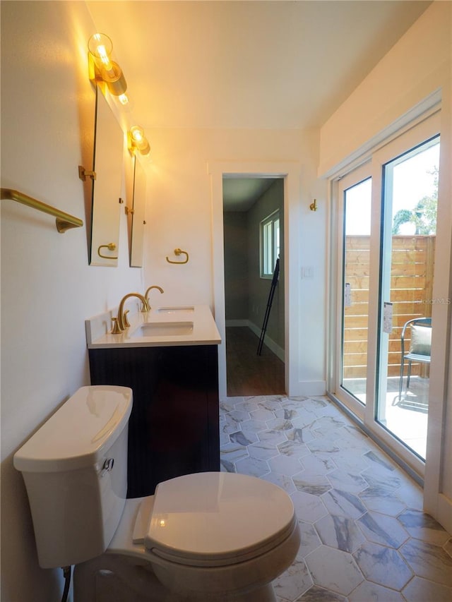 bathroom featuring vanity, baseboards, toilet, and stone floors