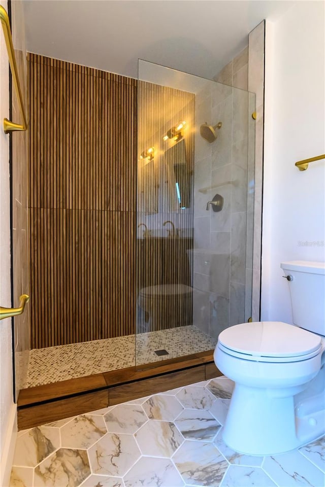 full bath featuring marble finish floor, a tile shower, and toilet