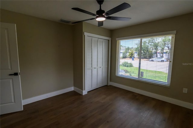 unfurnished bedroom featuring ceiling fan, baseboards, dark wood-type flooring, visible vents, and a closet