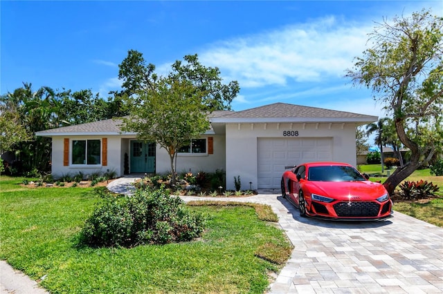 ranch-style house with an attached garage, decorative driveway, stucco siding, and a front yard
