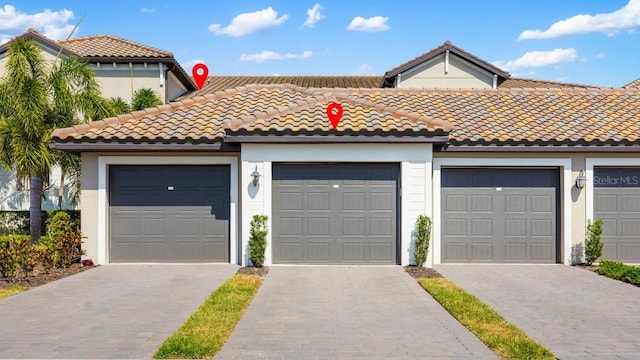 mediterranean / spanish home with a tiled roof, community garages, and stucco siding